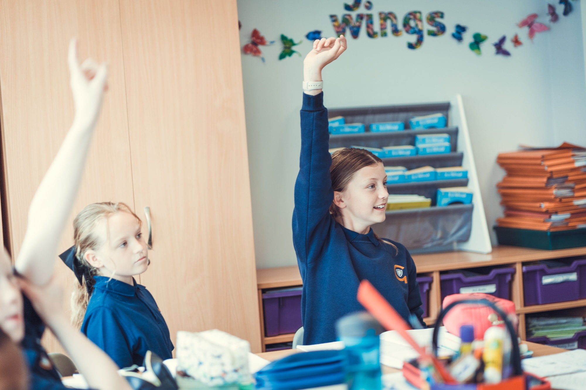 Children with hands up in the classroom